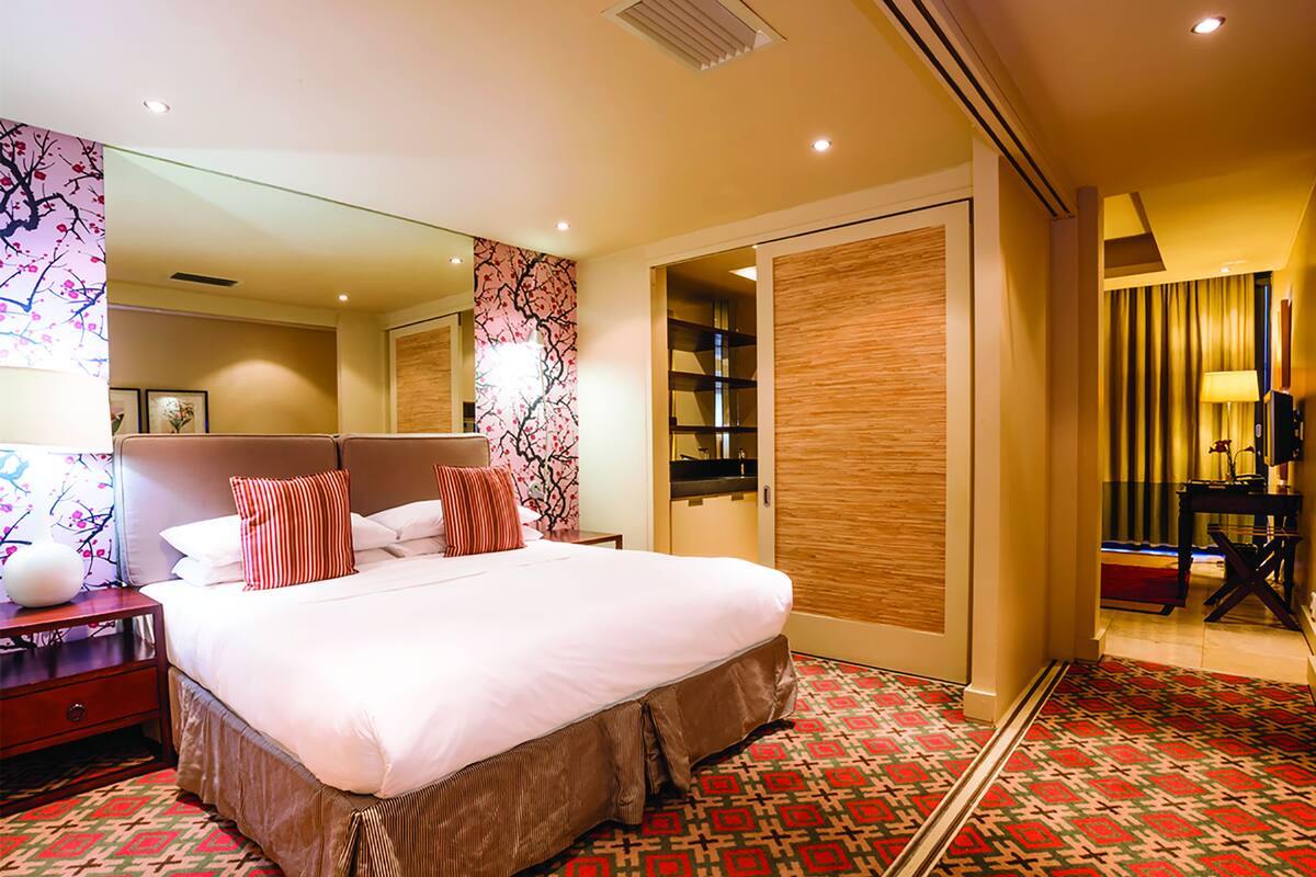 A hotel room with a large bed, a nightstand, a mirror, a wardrobe, and a patterned carpet.