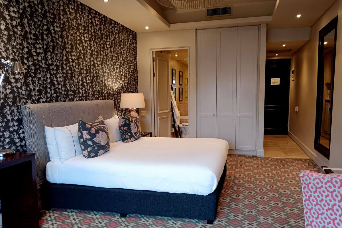 A hotel room with a large bed, a nightstand, a lamp, and a patterned carpet.