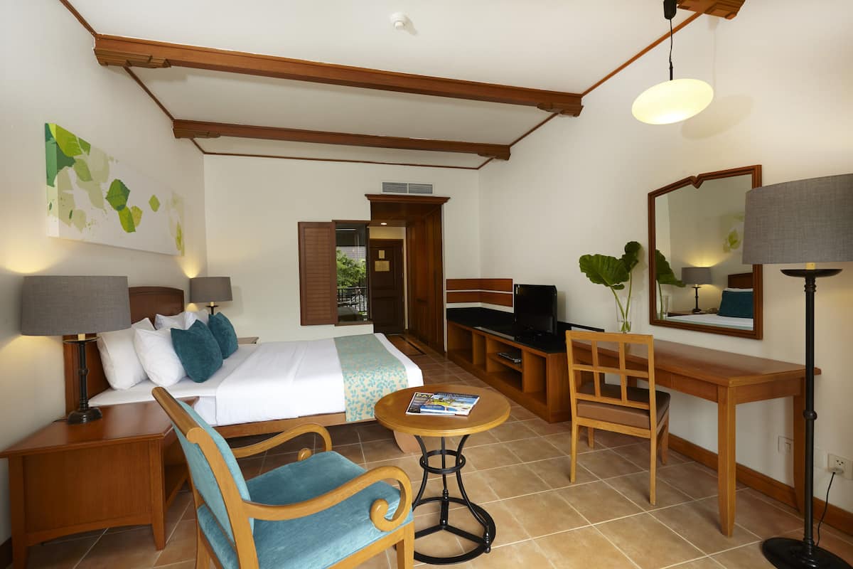 Une chambre d’hôtel équipée d’un lit, d’un bureau, d’une chaise, d’une table, d’une lampe et d’un miroir.