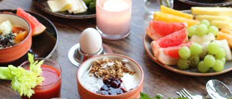 A breakfast setting with various dishes, including eggs, toast, and fruit, on a wooden table.