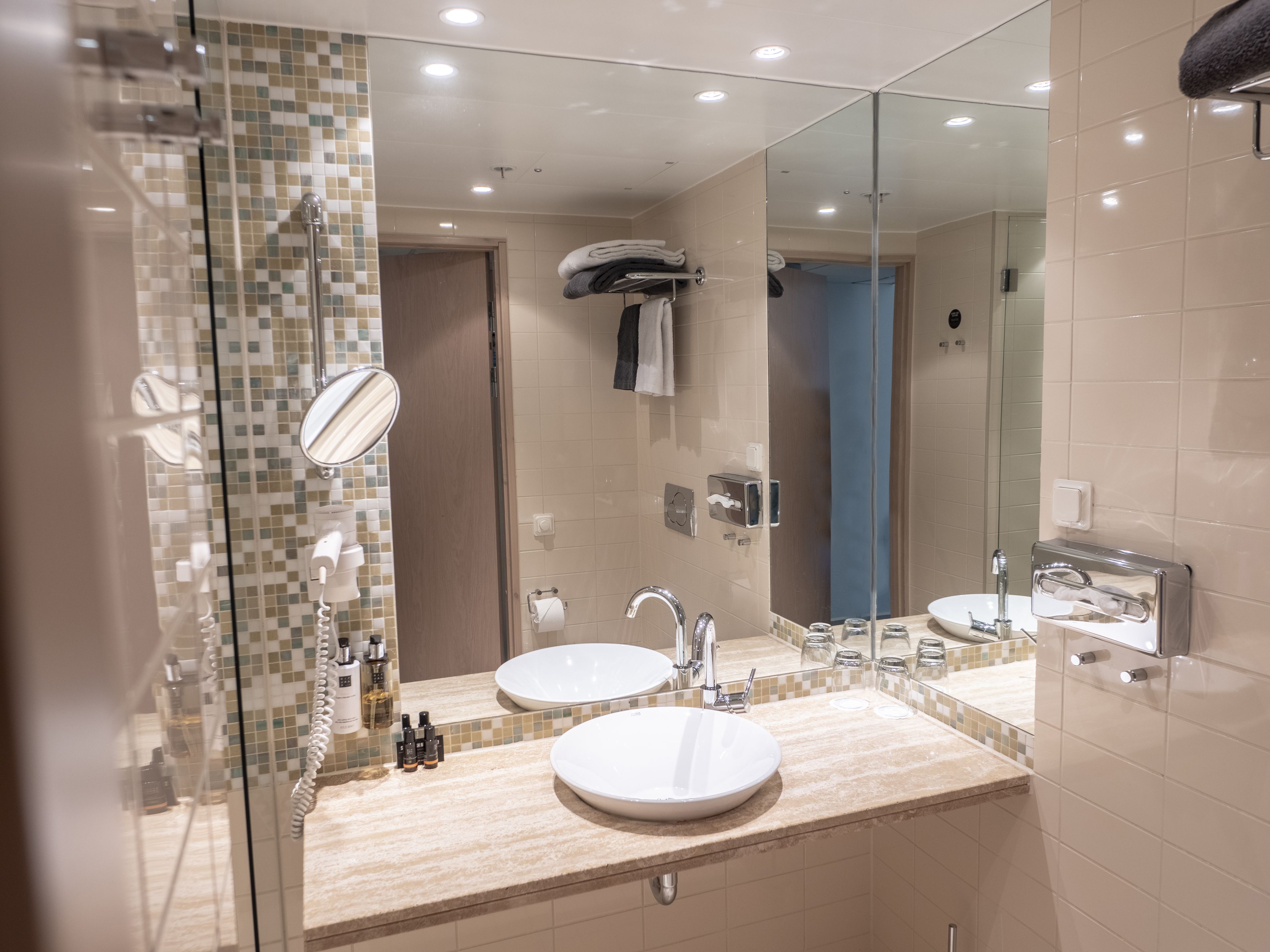 Un baño moderno con dos lavamanos, un espejo y una zona de ducha.
