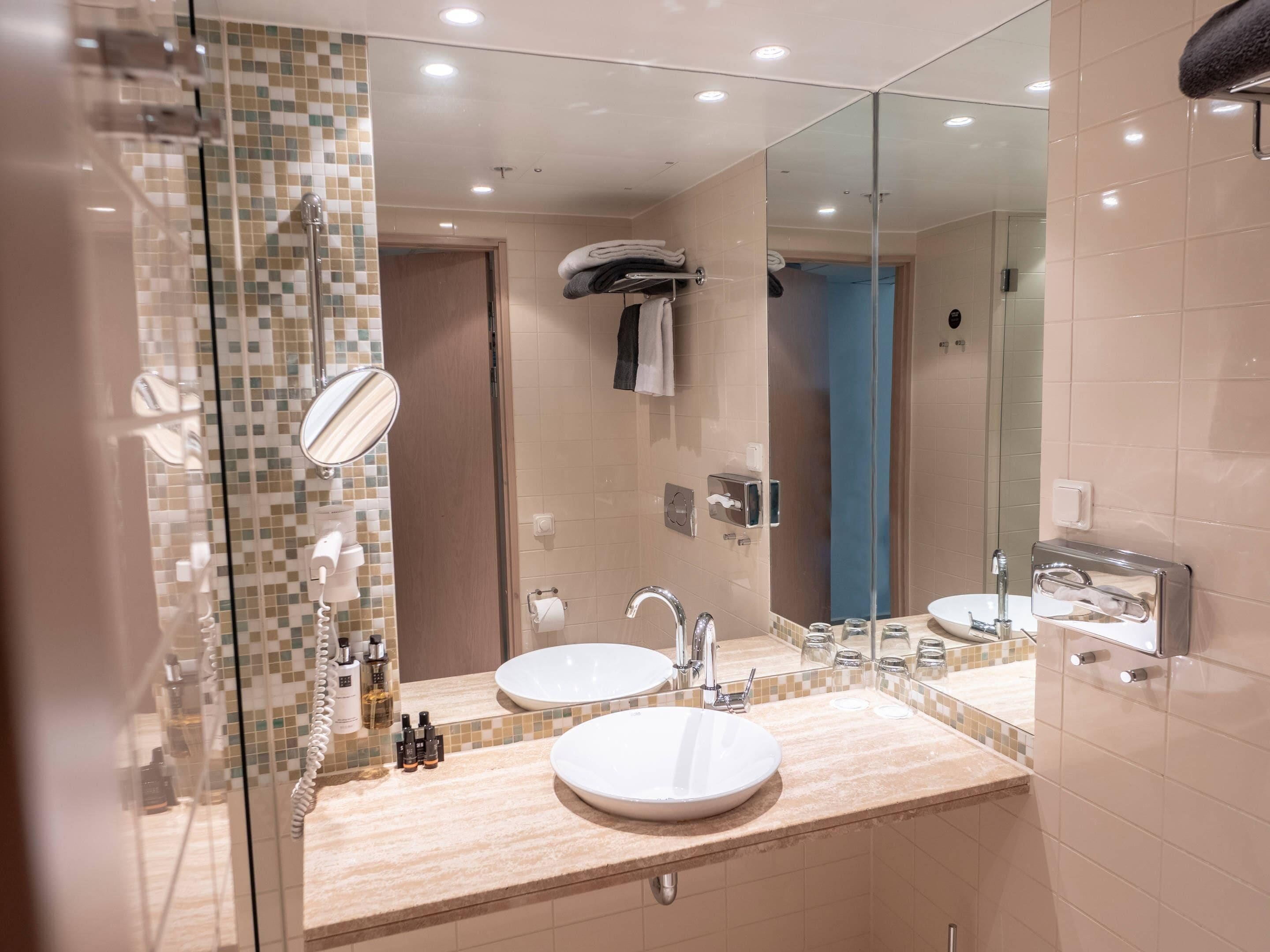 Un baño moderno con dos lavamanos, un espejo grande y una zona de ducha.
