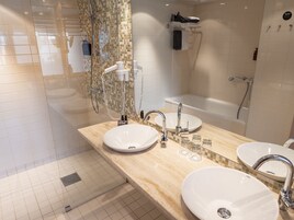 Un baño moderno con dos lavamanos, ducha y bañera.