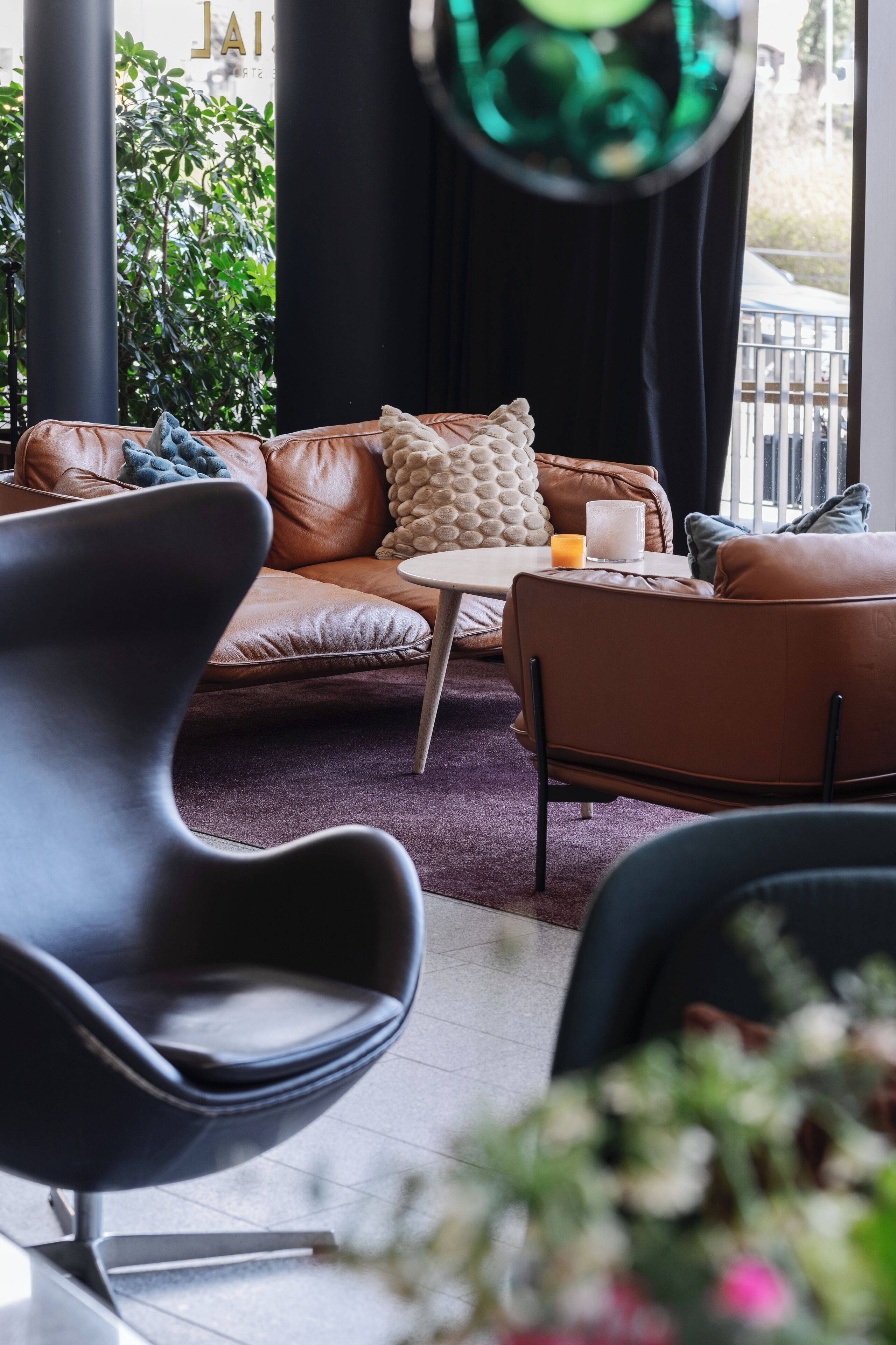 Una sala de estar moderna con un sofá de cuero marrón, una mesa de centro redonda y un sillón negro.