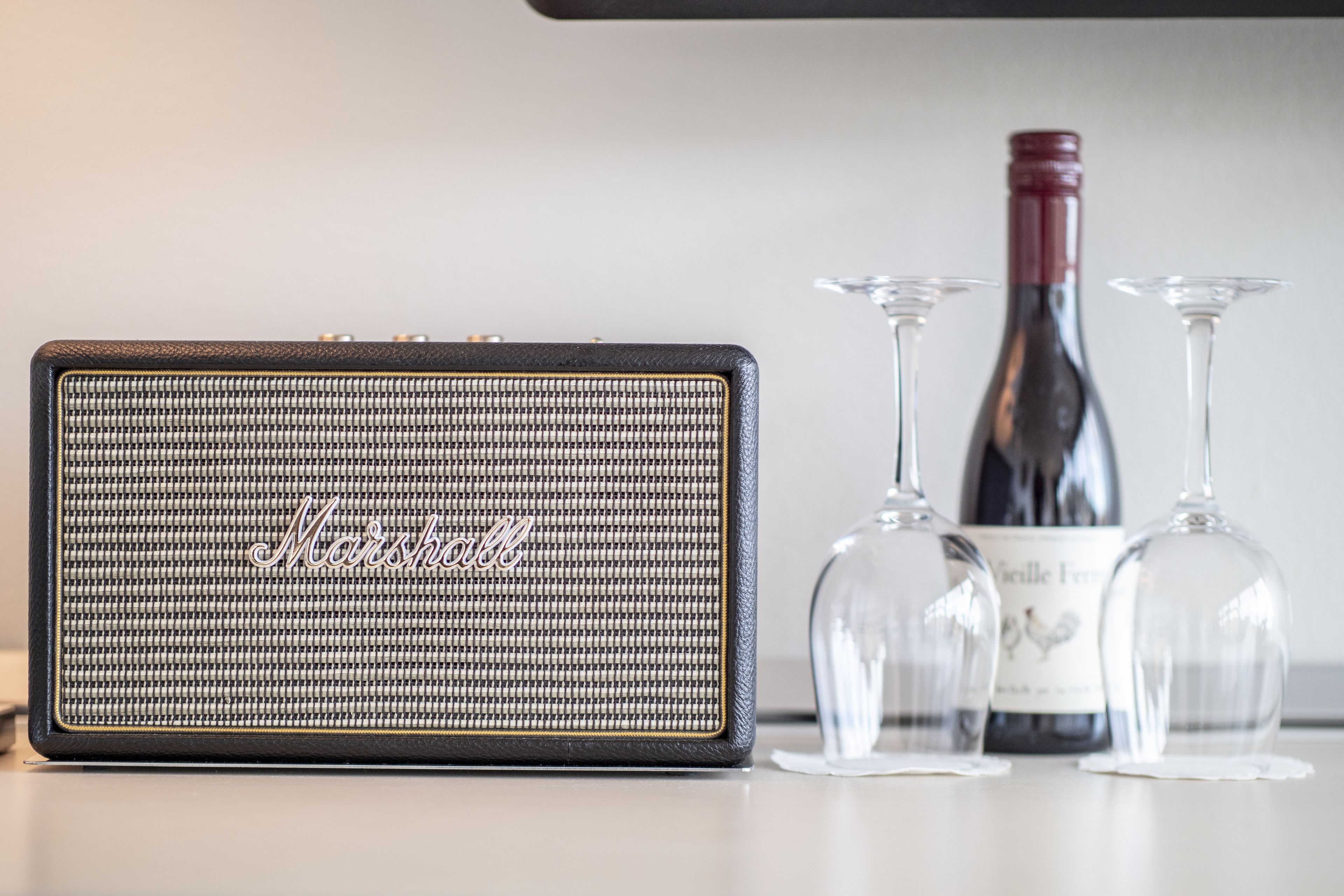 A Marshall amplifier, two wine glasses, and a bottle of wine on a table.