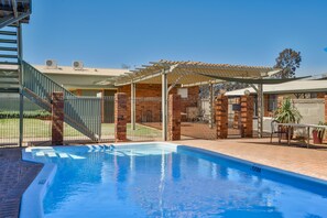 Una piscina al aire libre, sillones reclinables de piscina