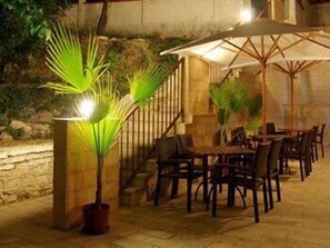 An outdoor dining area with tables and chairs, surrounded by stone walls and potted plants. - Valeo Hotel (Balchik)