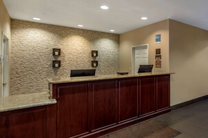 Una recepción con pared de textura de piedra, armarios de madera y una puerta.