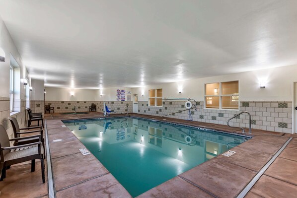 An indoor swimming pool with clear water, surrounded by a tiled wall and a wooden deck.