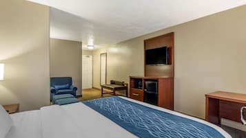 A hotel room with a large bed, a TV, a desk, and a chair.