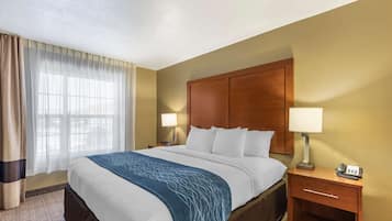 A hotel room with a large bed, two bedside tables, a nightstand, a lamp, and a telephone.