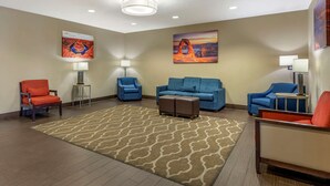 A hotel lobby with a large patterned rug, blue sofas, and orange chairs. - Comfort Inn Saint George North (St. George)