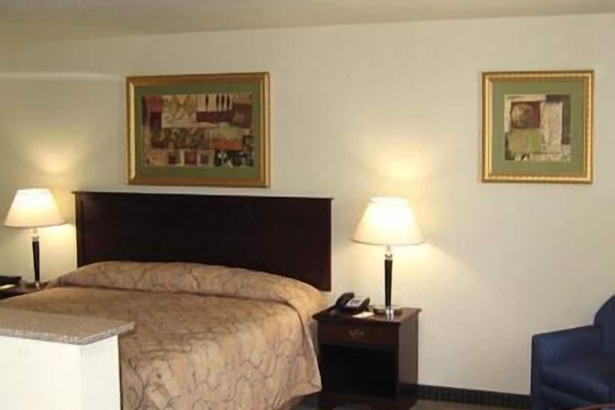 A hotel room with a bed, two bedside tables with lamps, a small table, and two chairs.