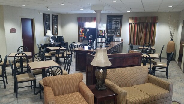 A hotel lobby with multiple seating areas, including sofas and chairs, a reception desk, and a coffee machine. - HomeTown Hotel Bryant (Bryant)
