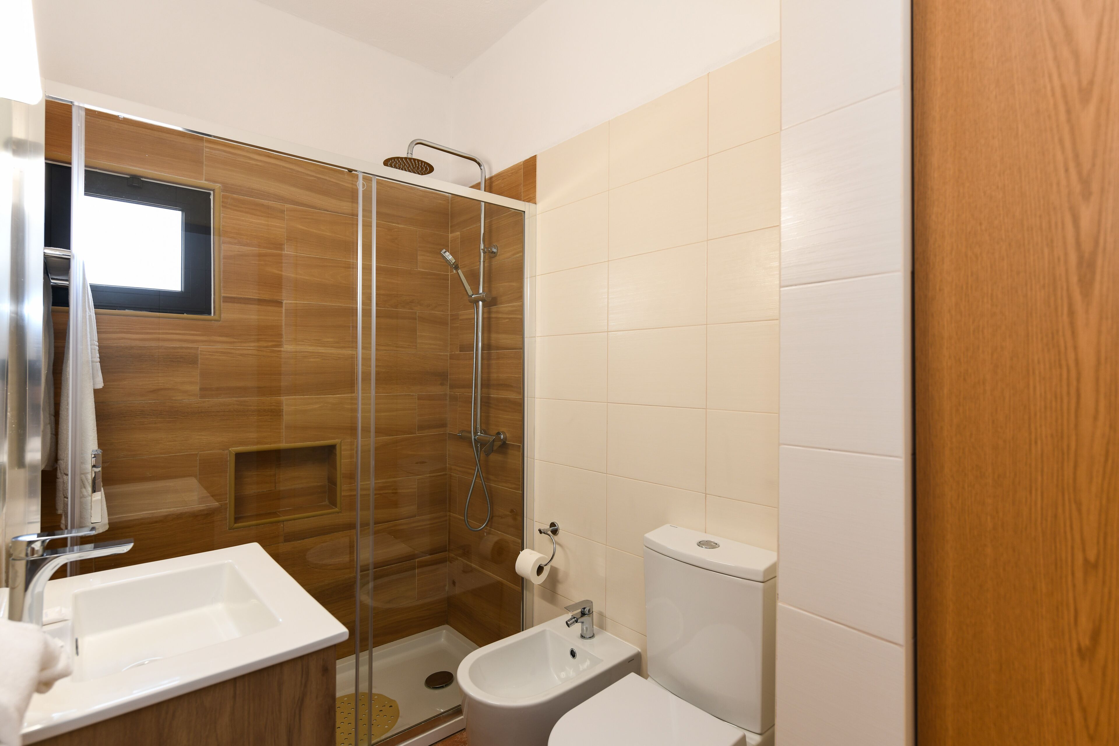 A modern bathroom with a glass-enclosed shower, a sink, and a toilet.