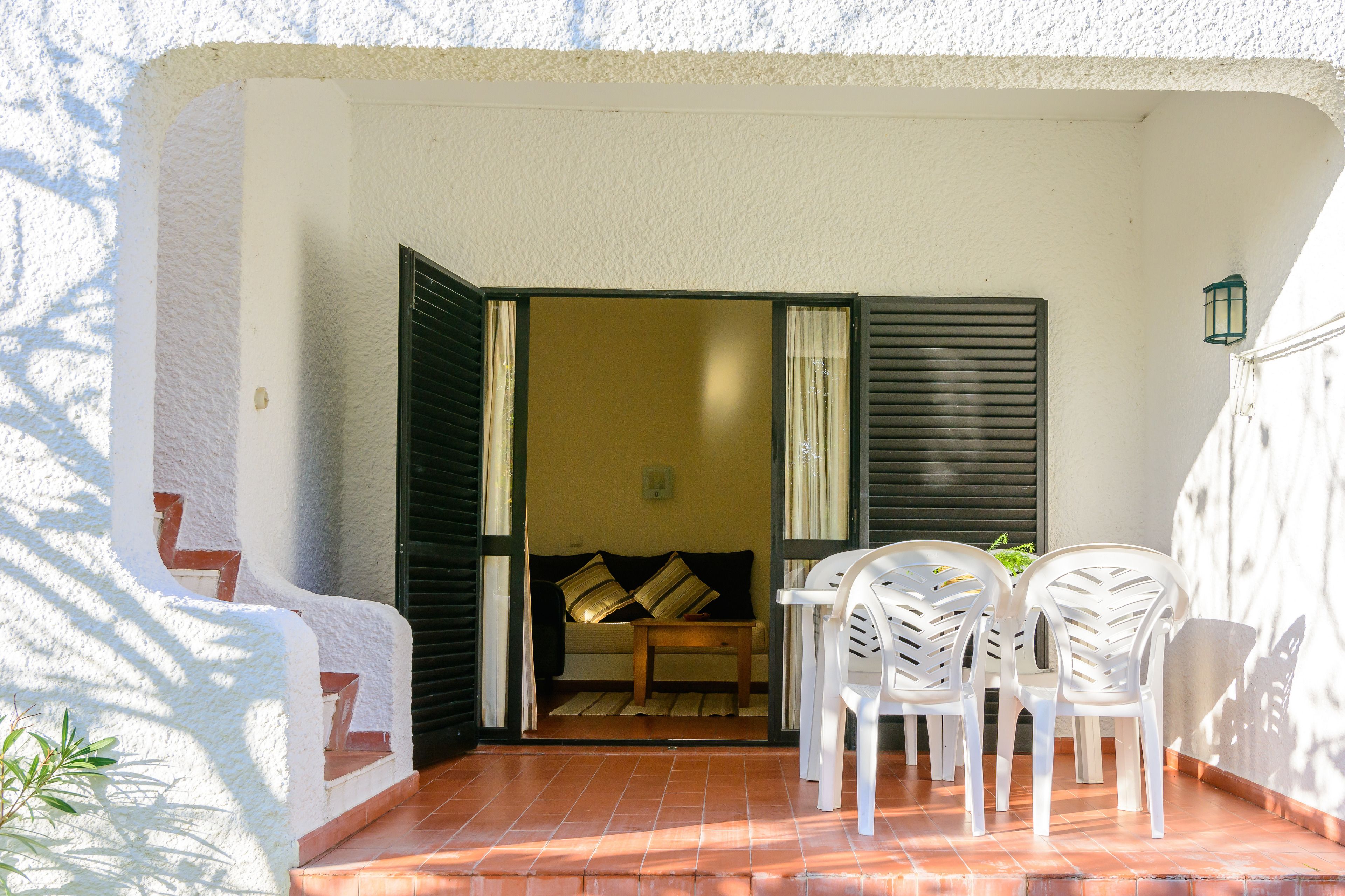A patio with a sofa, a table, and two chairs.
