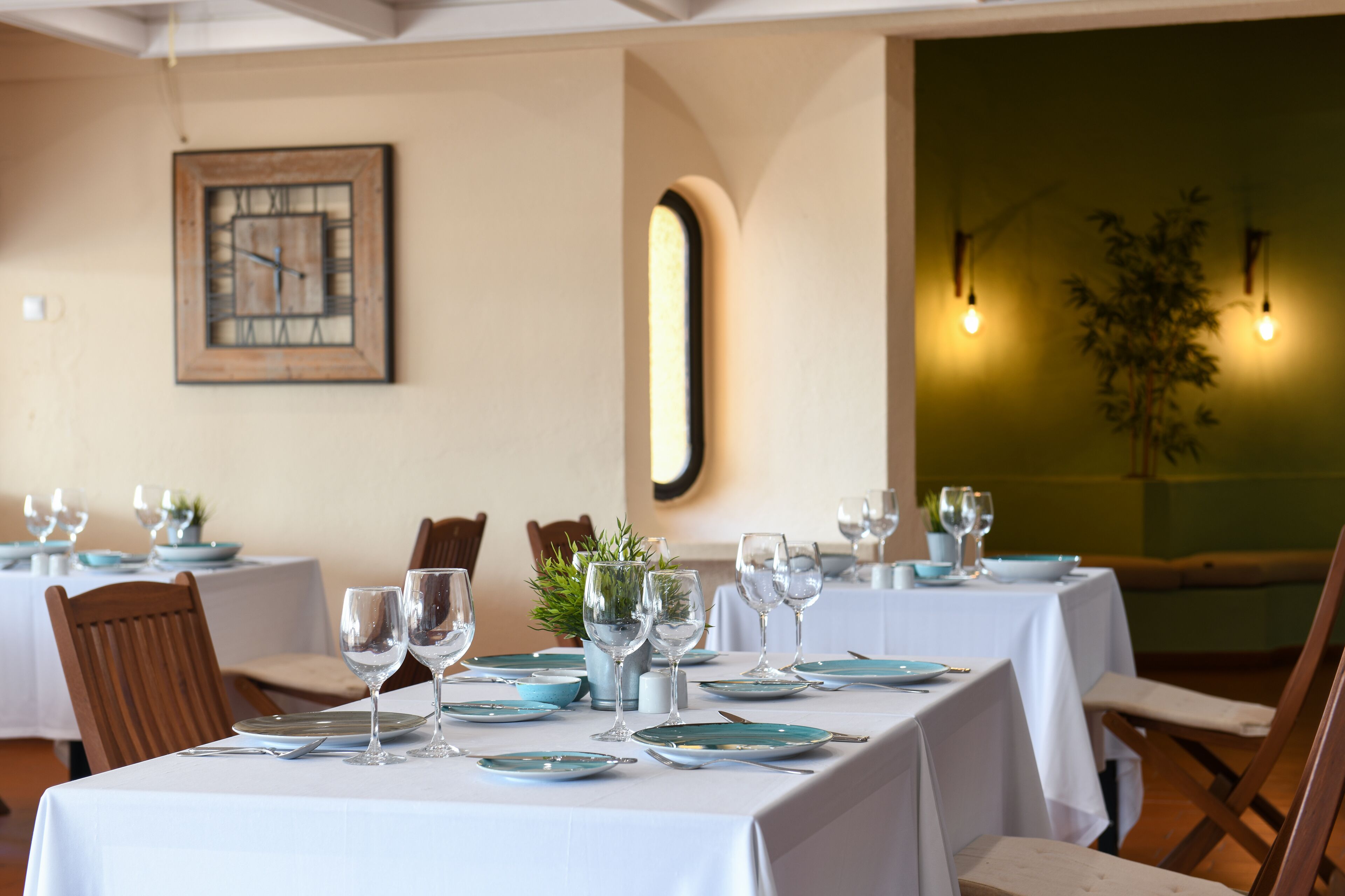 A dining area with tables set for a meal, chairs, and a clock on the wall.