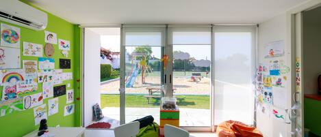 A classroom with a view of an outdoor playground, a white table with chairs, and a bean bag chair.