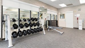Un gimnasio con jaulas para pesas, una banca y una cinta de correr.