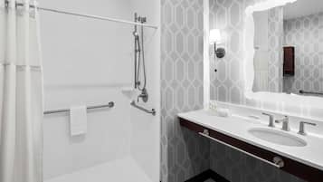 A modern bathroom with a shower, a vanity with a mirror, and a towel rack.