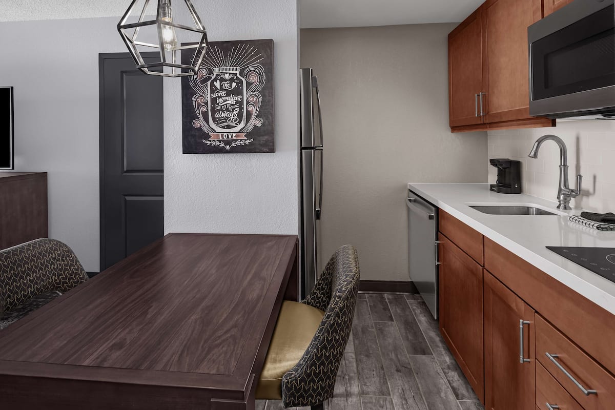A modern kitchen with wooden cabinets, a stainless steel refrigerator, and a white countertop.