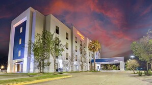 A hotel with a modern design, featuring a large entrance and a clear sky with clouds. - Hampton Inn Baton Rouge - Denham Springs (Denham Springs)