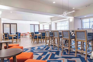 A spacious dining area with multiple tables and chairs, large windows, and a patterned carpet. - Hampton Inn Baton Rouge - Denham Springs (Denham Springs)