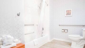 Baño con ducha, inodoro y toallero.