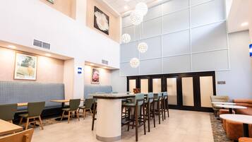 Un vestíbulo de hotel con área de estar, una recepción y un ventanal grande.