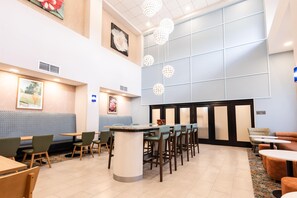 A hotel lobby with a seating area, a reception desk, and a large window.