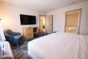 Une chambre d’hôtel comprenant un lit, un bureau, une chaise, une télévision et une salle de bain.