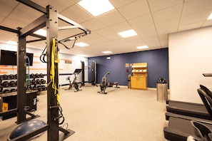 Un gimnasio con equipo de ejercicio, pesas y una pared azul.