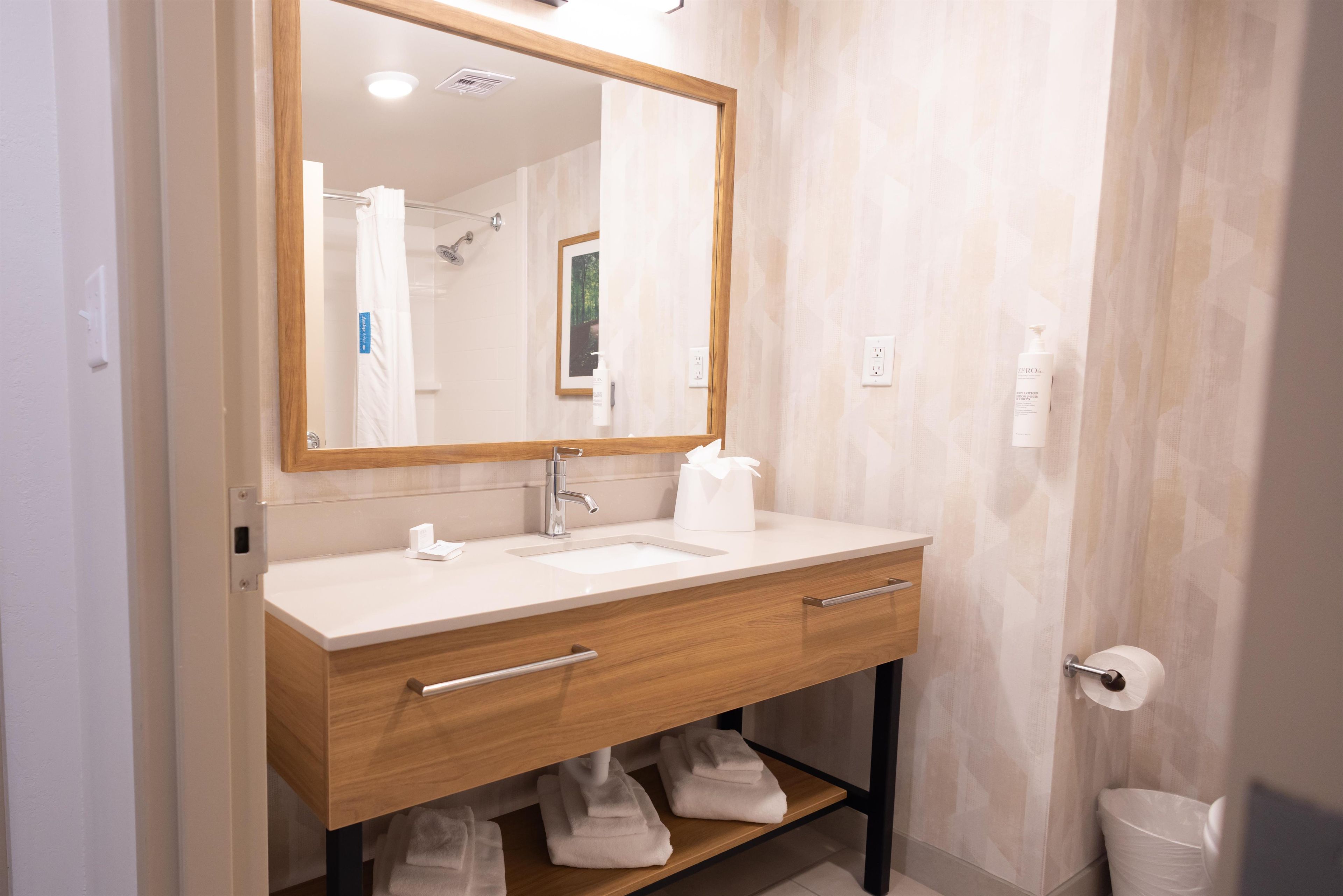 Une salle de bain moderne avec un meuble-lavabo en bois, un grand miroir et un lavabo blanc.