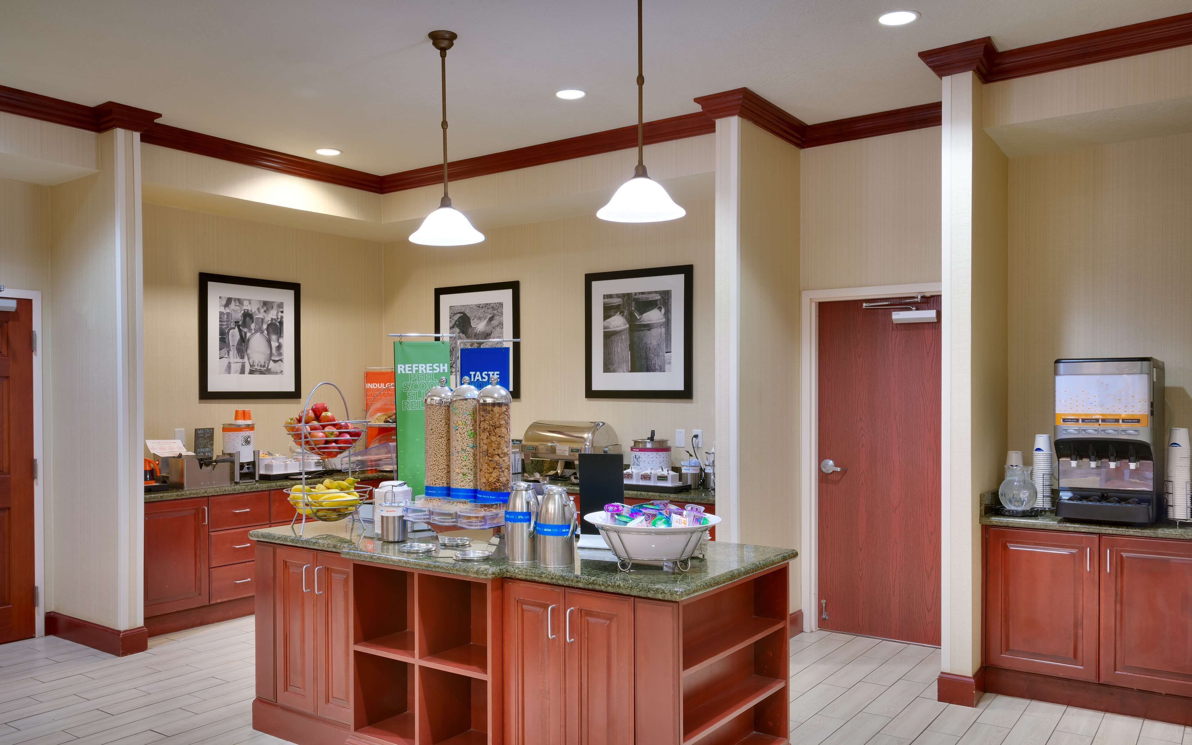 A hotel kitchen with a central island, equipped with various appliances and food items.