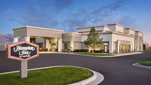 A Hampton Inn by Hilton hotel with a clear entrance, a signboard, and a parking lot.