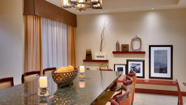 A dining area with a marble table, chairs, a candle centerpiece, and artwork on the walls.