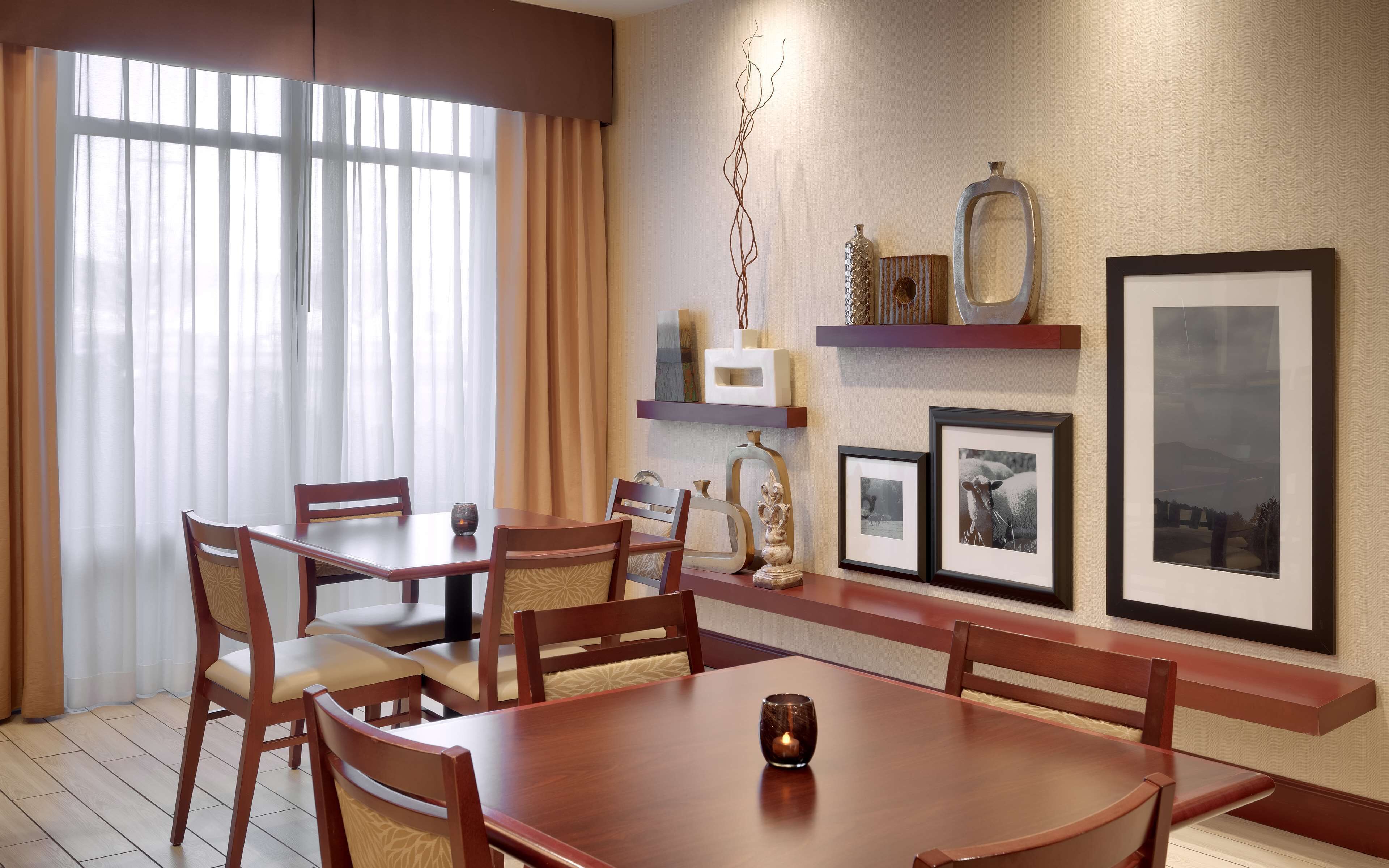A dining area with a wooden table and chairs, a candle on the table, and framed pictures on the wall.