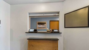 Una reception con una scrivania, un computer, una foto incorniciata e un bancone in legno.