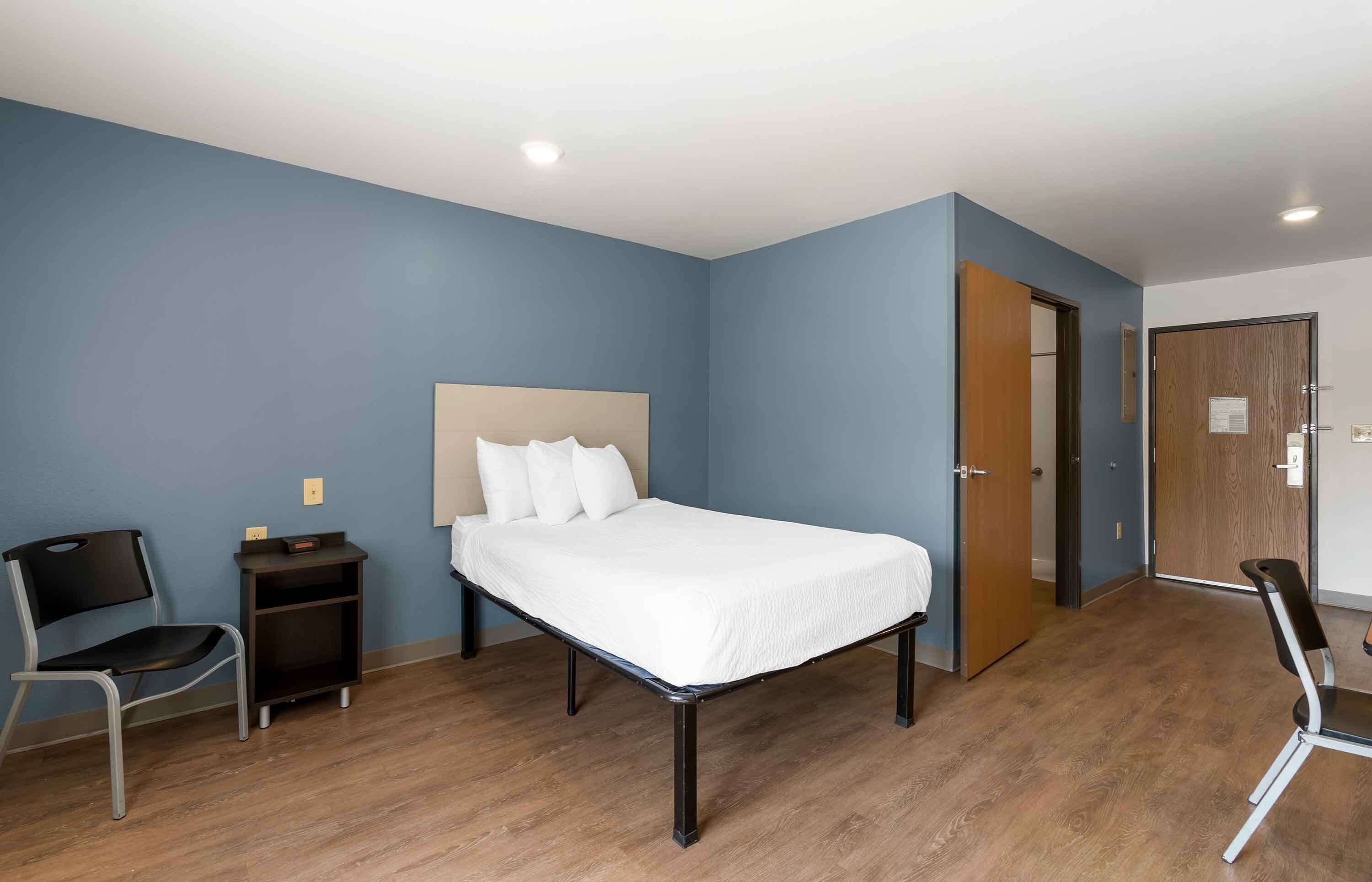 A hotel room with a bed, a desk, a chair, and a wardrobe.