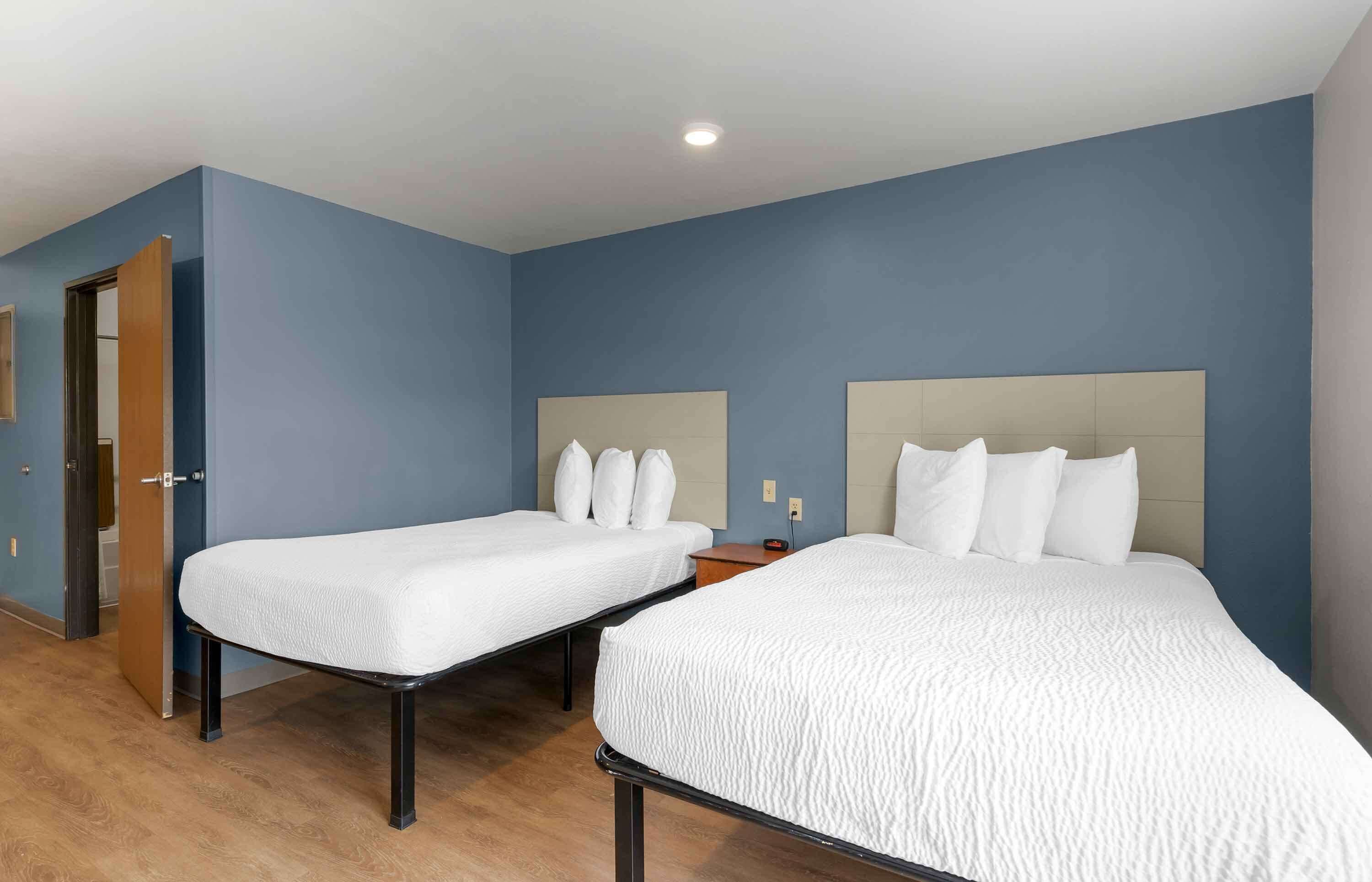 Une chambre d’hôtel avec deux lits simples, une porte en bois et un mur bleu.