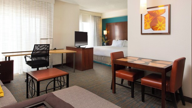 Habitación de hotel con cama, escritorio, televisor y zona de estar.