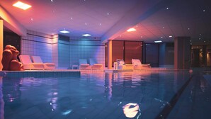 Una piscina interior con sillones de descanso y un diseño moderno.