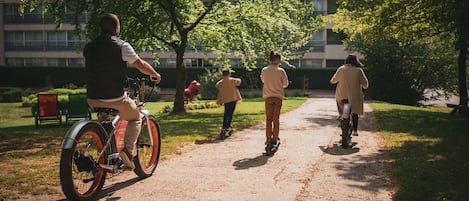 A pathway in a park with people riding bicycles and rollerblades.