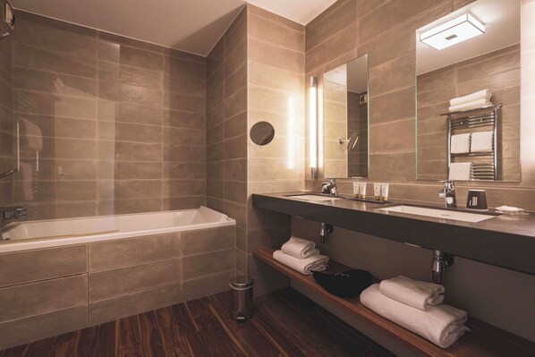 Ein modernes Badezimmer mit einer Badewanne, zwei Waschbecken und einem Waschtisch inklusive Spiegel.