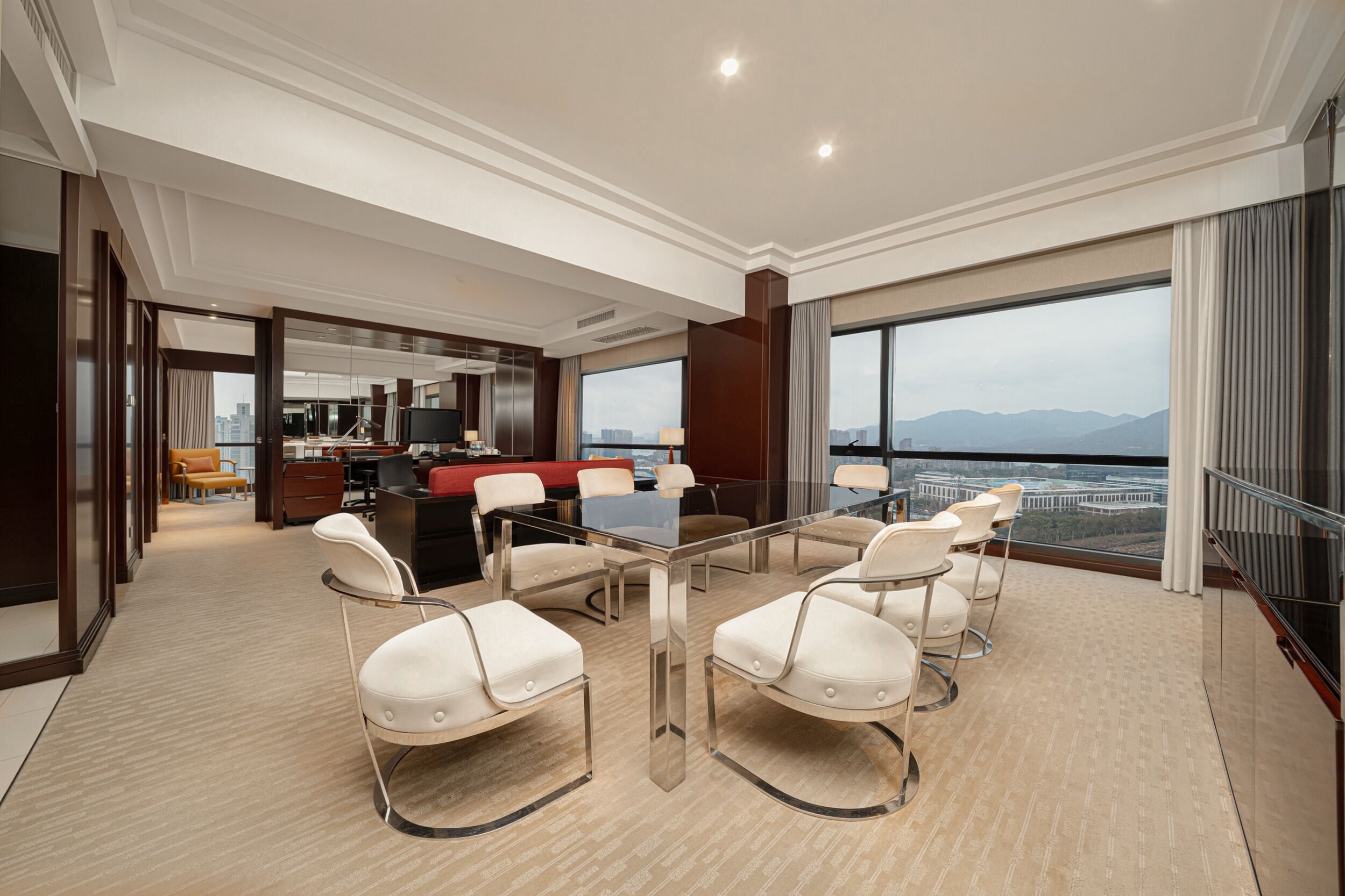 Une chambre d’hôtel moderne dotée d’un coin repas, d’une grande fenêtre offrant une vue sur la ville et d’un balcon.