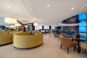A modern hotel lobby with curved seating, a bar area, and a large mirror reflecting the space. - Four Points by Sheraton Hangzhou, Binjiang (Hangzhou)