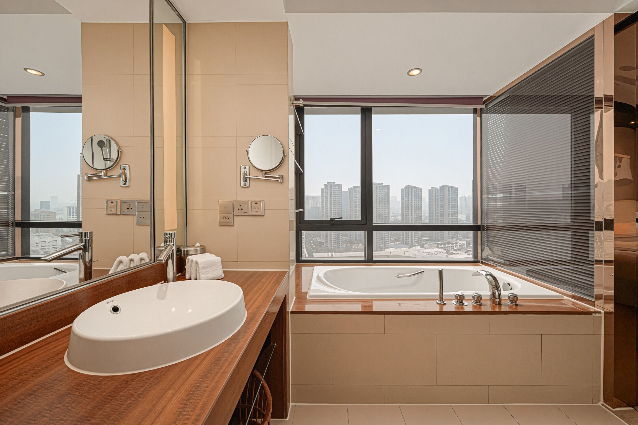 A modern bathroom with a large mirror, two sinks, and a bathtub.