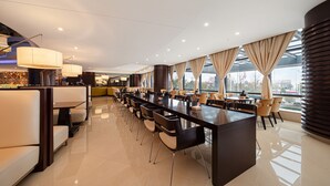 Un lobby moderno de hotel con un mostrador de recepción amplio, varias zonas de estar y grandes ventanales con vistas a la ciudad.
