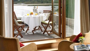 A dining area with a table set for two, overlooking a scenic view of a lake and mountains. - Sneem Hotel (Sneem)