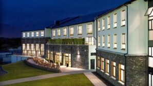 A multi-story building with a well-lit facade, a landscaped garden area, and a clear sky. - Sneem Hotel (Sneem)